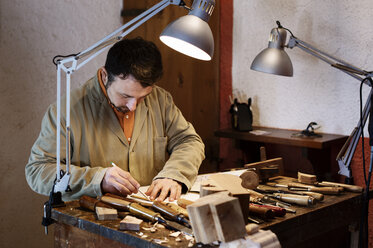 Handwerker beim Entwurf einer Figur auf dem Tisch in der Werkstatt - CAVF33551