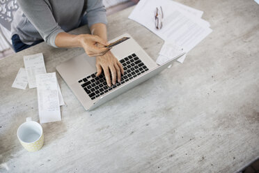 High angle view of woman holding debit card and using laptop on table - CAVF33563