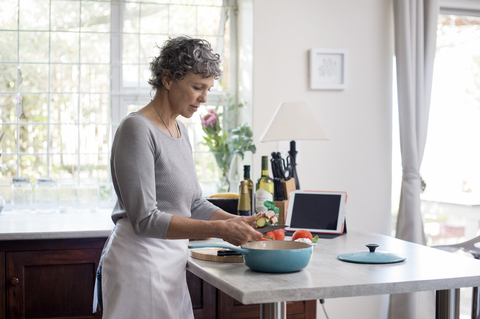 Ältere Frau hackt Gemüse in der Küche, lizenzfreies Stockfoto