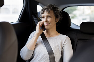Reife Frau, die im Auto sitzend mit ihrem Handy telefoniert - CAVF33570