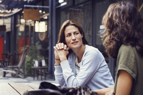 Ältere Frau im Gespräch mit einem Freund in einem Straßencafé, lizenzfreies Stockfoto