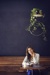 Portrait of happy woman sitting at cafe table - CAVF33606