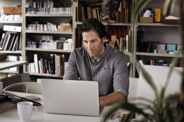 Männlicher Innenarchitekt mit Laptop am Schreibtisch im Büro - CAVF33619