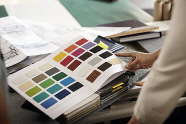 Ausgeschnittenes Bild eines Innenarchitekten, der Farbmuster im Büro untersucht - CAVF33630