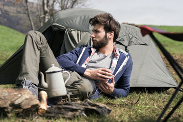 Thoughtful man relaxing outside tent on hill - CAVF33667