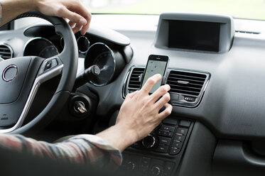 Ausgeschnittenes Bild eines Mannes, der im Auto GPS auf seinem Smartphone benutzt - CAVF33680