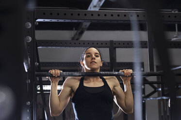 Niedriger Blickwinkel der entschlossenen Sportlerin übt auf Affenbarren im Fitnessstudio - CAVF33699