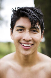 Porträt eines glücklichen Mannes ohne Hemd mit nassen Haaren im Garten - CAVF33718