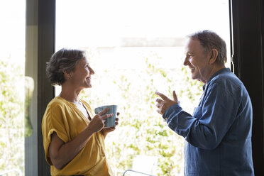 Side view of senior couple having coffee by window at home - CAVF33766