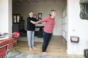 Senior man assisting woman in doing yoga - CAVF33779