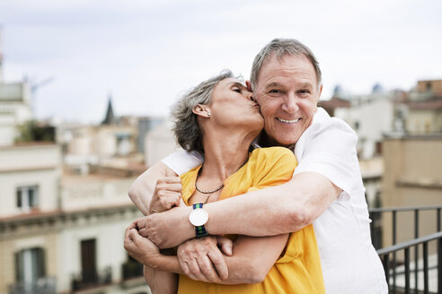 Romantische reife Frau küsst älteren Mann auf Terrasse - CAVF33812