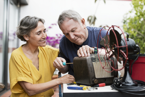 Älteres Ehepaar repariert altmodisches Radio auf der Werft, lizenzfreies Stockfoto