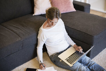 Reife Frau beim Schreiben mit dem Laptop zu Hause - CAVF33850