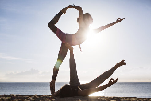 Paar macht Yoga am Strand gegen den Himmel im Sommer - CAVF33865