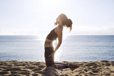 Seitenansicht einer entschlossenen Frau, die im Sommer am Ufer Yoga macht - CAVF33875