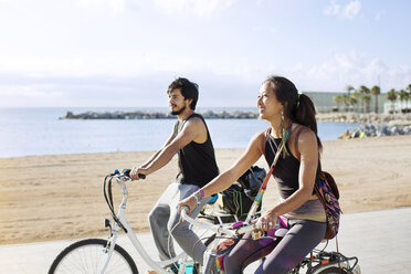 Sportliches Paar auf Fahrrädern auf der Straße am Strand - CAVF33878