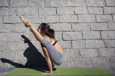 Entschlossene Frau macht Arm-Balance-Yoga-Pose auf dem Bürgersteig - CAVF33892