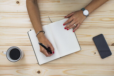 Overhead view of businesswoman writing in diary at office desk - CAVF33900