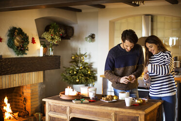 Lächelndes Paar beim Schmücken des Hauses zu Weihnachten - CAVF33932