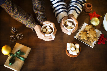 Cropped image of couple having marshmallow coffee with cookies at table - CAVF33935