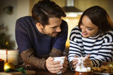 Smiling couple having coffee marshmallow at table during Christmas - CAVF33936