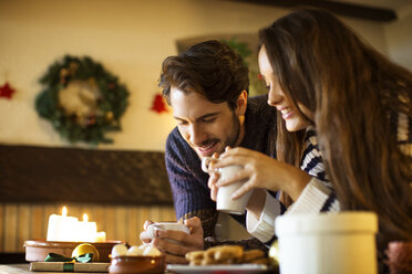 Smiling couple having coffee at table during Christmas - CAVF33938