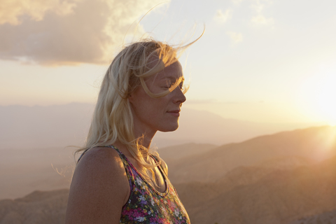 Weibliche Touristin entspannt in Berglandschaft bei Sonnenuntergang, lizenzfreies Stockfoto