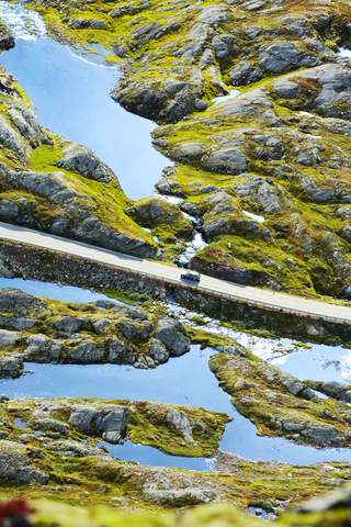 Blick auf den Geirangerfjord mit einem einsamen Auto auf der Straße Trollstigen, lizenzfreies Stockfoto