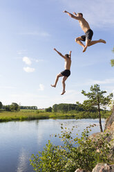 Junger Mann und Jugendlicher springen in den Fluss Svartan - FOLF07974