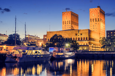 Beleuchtetes Osloer Rathaus, das sich in der Abenddämmerung im Hafen spiegelt - FOLF07996