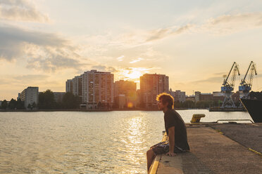 Man sitting on pier at sunset - FOLF08075