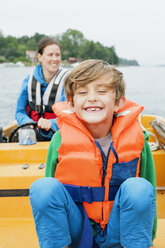 Porträt eines Jungen auf einem Motorboot, Mutter im Hintergrund - FOLF08098
