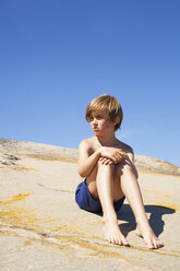 Porträt eines auf einem Felsen sitzenden Jungen im Sommer - FOLF08100