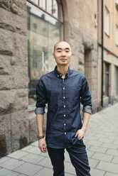 Smiling young man on sidewalk - FOLF08304