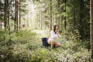 Young woman making picture with camera in forest - FOLF08324