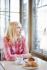 Woman looking through cafe window, smiling - FOLF08369