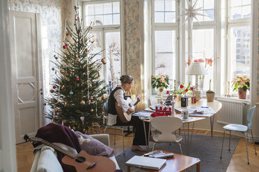 Ältere Frau spielt Gitarre im Wohnzimmer - FOLF08397