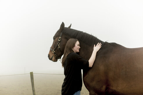 Halbwüchsige Frau mit Pferd auf unbefestigtem Weg im Nebel - FOLF08414