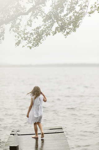 Mädchen steht auf Steg am See, lizenzfreies Stockfoto