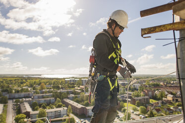 Side view of strong firefighter in protective equipment during training  with ropes near building on background of blue sky stock photo