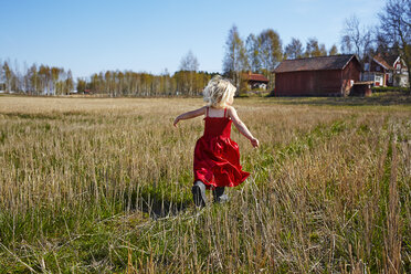 Girl wearing red dress running in field - FOLF08509