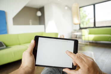 Businessman using tablet at home, typing on display - PESF01016