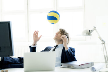 Businessman playing with a ball in his office - HHLMF00167