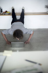 Businessman working from home with his laptop, while doing a plank - HHLMF00173