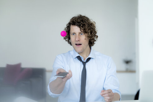 Businessman playing ping pong with a ball and his mobile phone - HHLMF00196