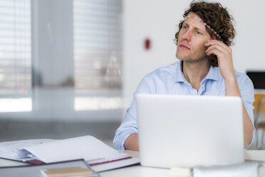 Businessman with headband dreaming at his desk - HHLMF00207