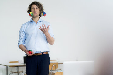 Smiling businessman juggling balls in his office - HHLMF00213