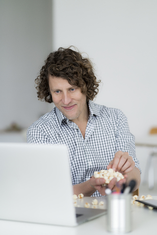 Geschäftsmann isst Popcorn in seinem Büro, lizenzfreies Stockfoto