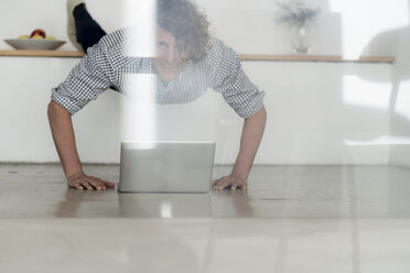 Businessman working from home with his laptop, while doing a plank - HHLMF00233