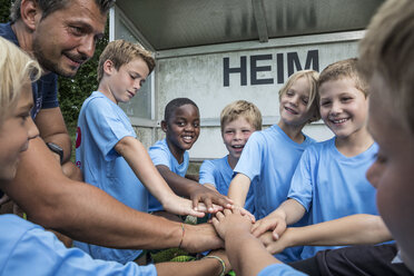 Coach and young football players huddling - WESTF24033